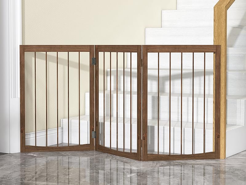 Wooden foldable pet or baby gate installed at bottom of white staircase, featuring vertical slats and accordion-style design.