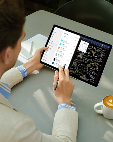 Hands holding tablet device displaying colorful gaming content on wooden surface.