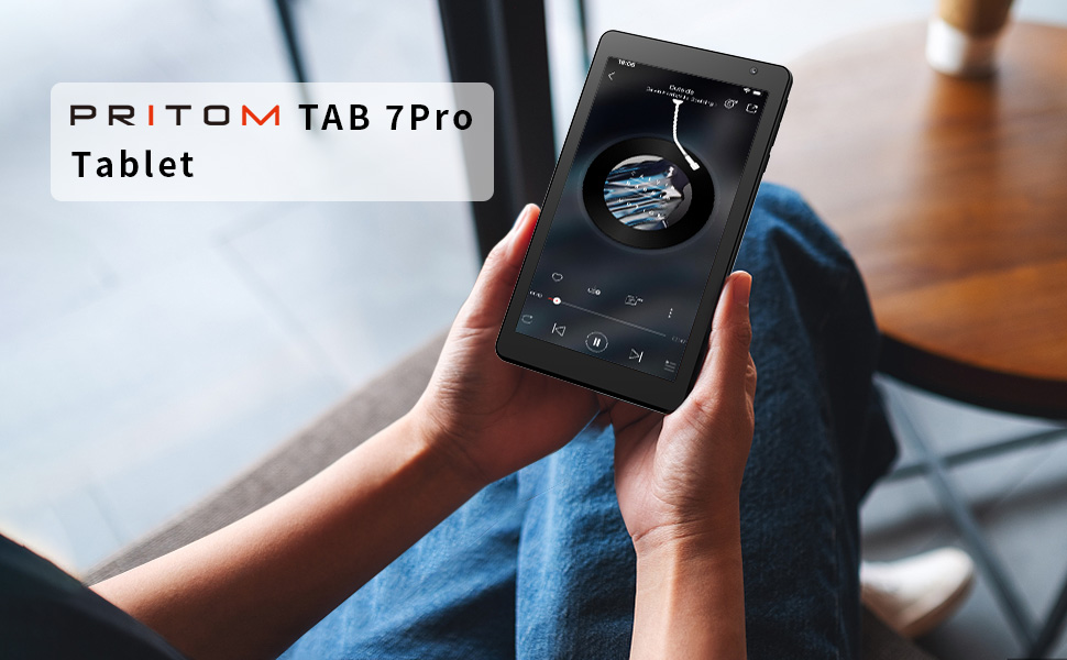 Hands holding Pritom Tab 7Pro tablet, displaying music interface on screen. Device shown in use against wooden surface background.