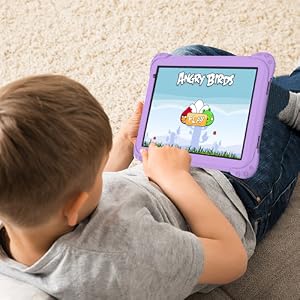 Young child in light blue shirt holding pink and purple tablet device with character design while sitting on floor with couch and people in background.